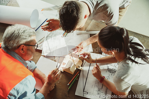 Image of Foreman or achitect shows house, office or store design plans to a young couple