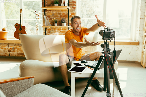 Image of Caucasian male blogger with camera recording video review of gadgets at home