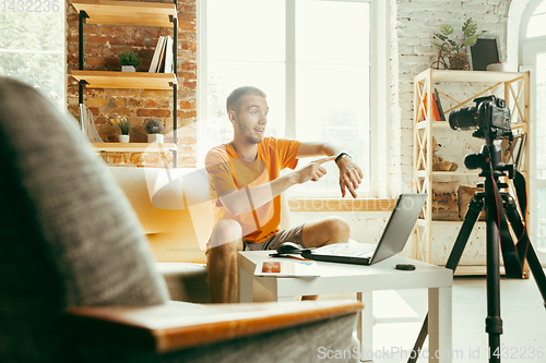 Image of Caucasian male blogger with camera recording video review of gadgets at home