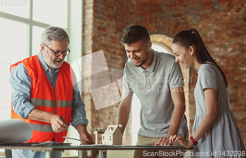 Image of Foreman or achitect shows house, office or store design plans to a young couple