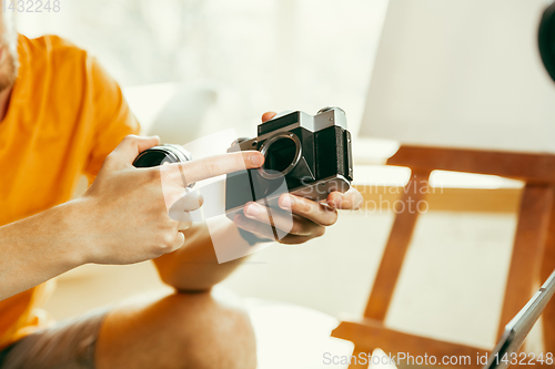 Image of Caucasian male blogger with camera recording video review of gadgets at home