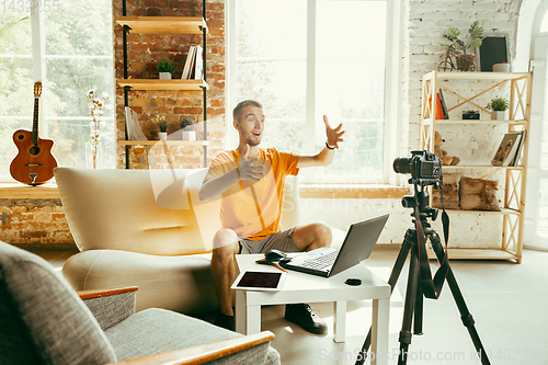 Image of Caucasian male blogger with camera recording video review of gadgets at home