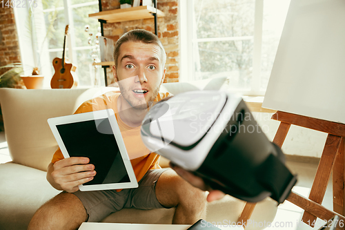 Image of Caucasian male blogger with camera recording video review of gadgets at home