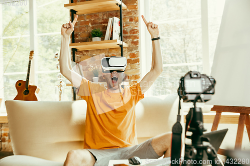 Image of Caucasian male blogger with camera recording video review of gadgets at home