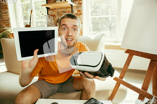 Image of Caucasian male blogger with camera recording video review of gadgets at home