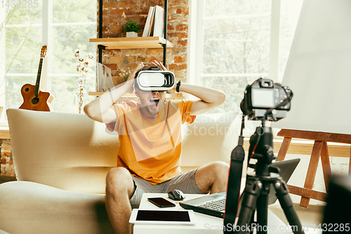 Image of Caucasian male blogger with camera recording video review of gadgets at home