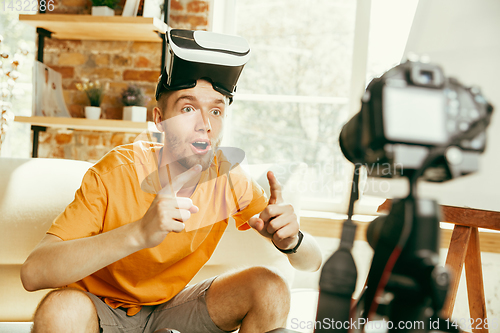 Image of Caucasian male blogger with camera recording video review of gadgets at home