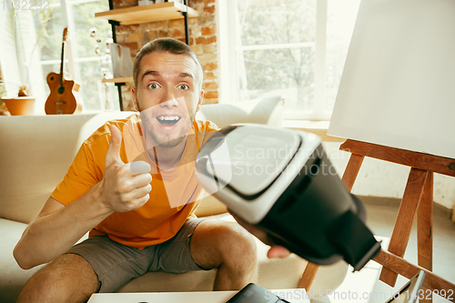 Image of Caucasian male blogger with camera recording video review of gadgets at home