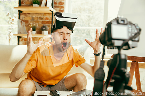 Image of Caucasian male blogger with camera recording video review of gadgets at home