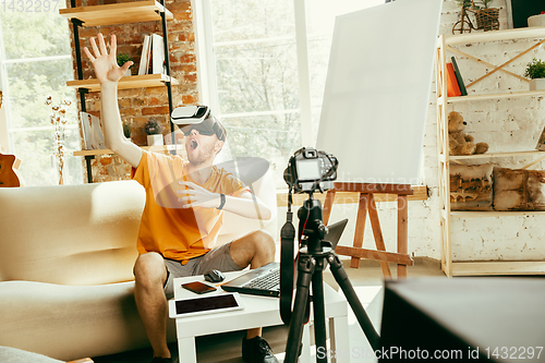 Image of Caucasian male blogger with camera recording video review of gadgets at home