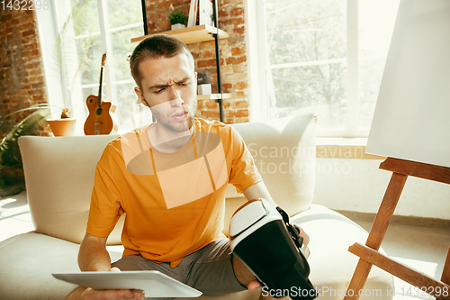 Image of Caucasian male blogger with camera recording video review of gadgets at home