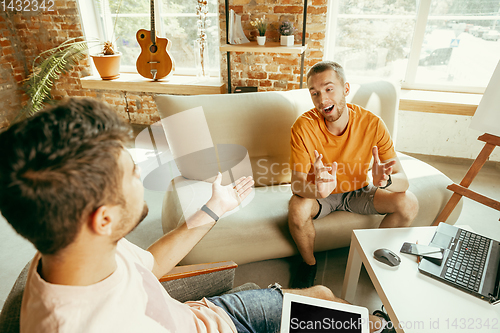 Image of Two young male bloggers with professional camera recording video interview at home