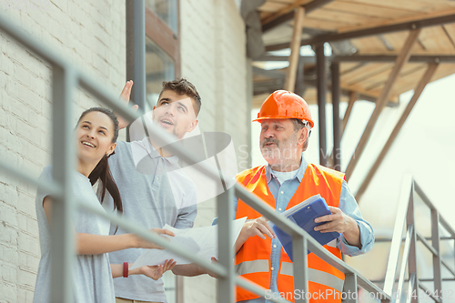 Image of Foreman or achitect shows house, office or store design plans to a young couple