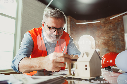 Image of Close up of male architect-engineer making a model of house