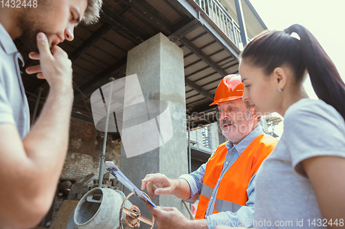 Image of Foreman or achitect shows house, office or store design plans to a young couple