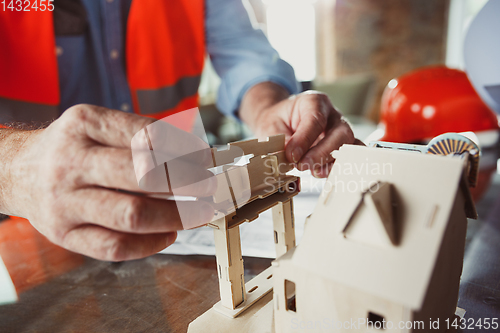 Image of Close up of male architect-engineer making a model of house