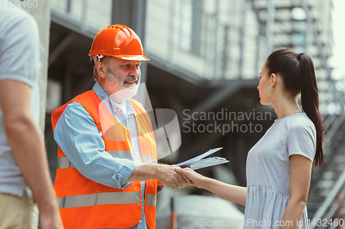 Image of Foreman or achitect shows house, office or store design plans to a young couple