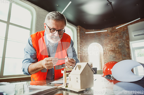 Image of Close up of male architect-engineer making a model of house