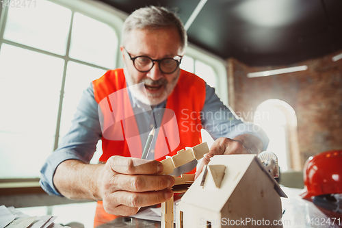 Image of Close up of male architect-engineer making a model of house