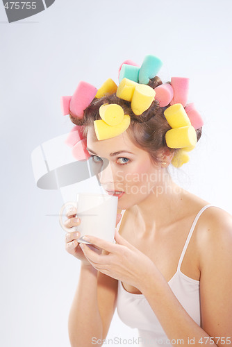 Image of A woman in hair curlers with a cup