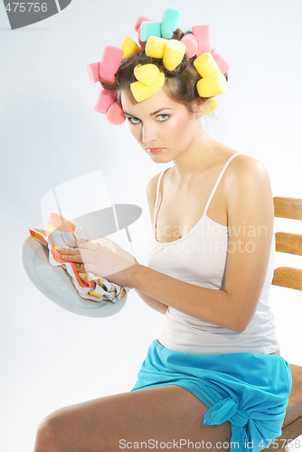 Image of A woman in hair curlers is drying up the plate