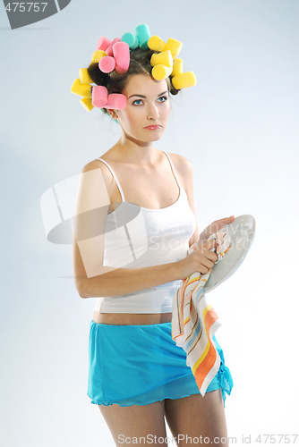 Image of A woman in hair curlers is drying up the plate