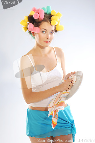 Image of A woman in hair curlers is drying up the plate