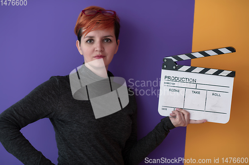Image of redhead woman holding movie  clapper on purple background