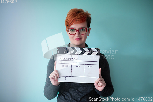 Image of redhead woman holding movie  clapper on cyan background