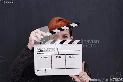 Image of redhead woman holding clapper on black background