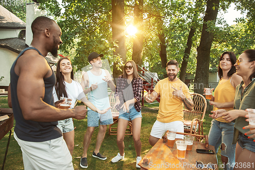 Image of Happy friends are having beer and barbecue party at sunny day