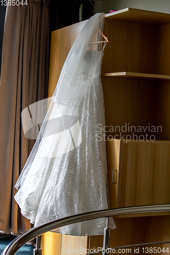 Image of Bridal dress hanging at wooden closet