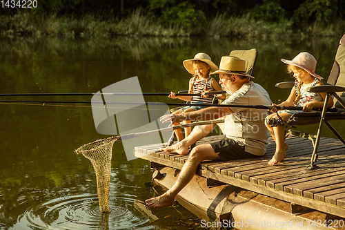 Image of Cute little girls and their granddad are on fishing at the lake or river