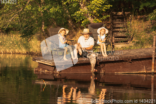 Image of Cute little girls and their granddad are on fishing at the lake or river