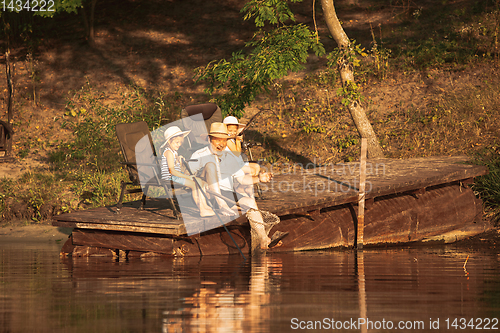 Image of Cute little girls and their granddad are on fishing at the lake or river