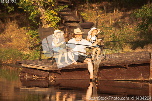 Image of Cute little girls and their granddad are on fishing at the lake or river