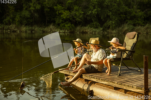 Image of Cute little girls and their granddad are on fishing at the lake or river