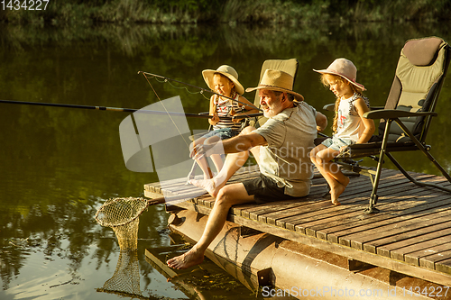 Image of Cute little girls and their granddad are on fishing at the lake or river