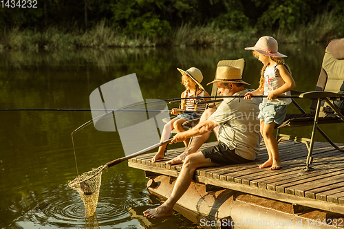 Image of Cute little girls and their granddad are on fishing at the lake or river