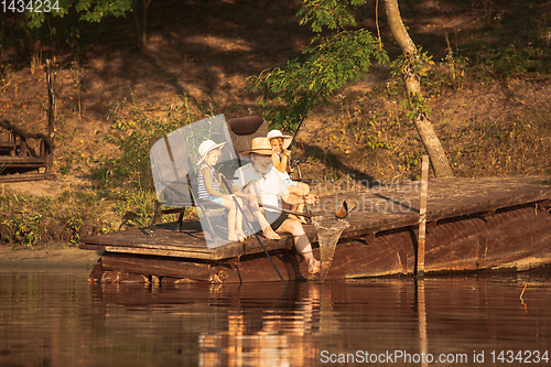 Image of Cute little girls and their granddad are on fishing at the lake or river