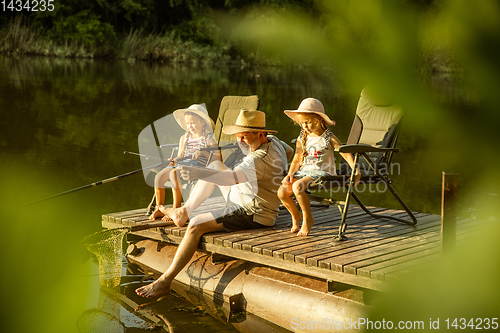 Image of Cute little girls and their granddad are on fishing at the lake or river