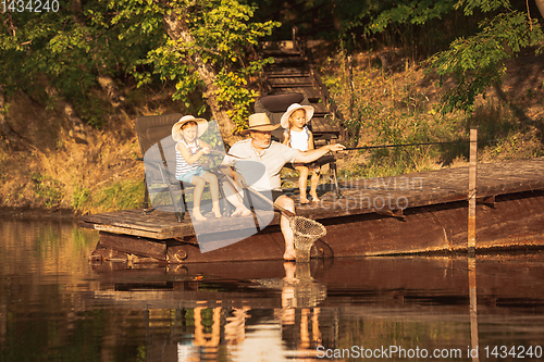 Image of Cute little girls and their granddad are on fishing at the lake or river