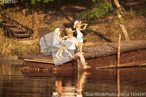 Image of Cute little girls and their granddad are on fishing at the lake or river