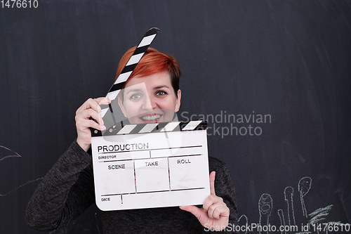 Image of redhead woman holding clapper on black background
