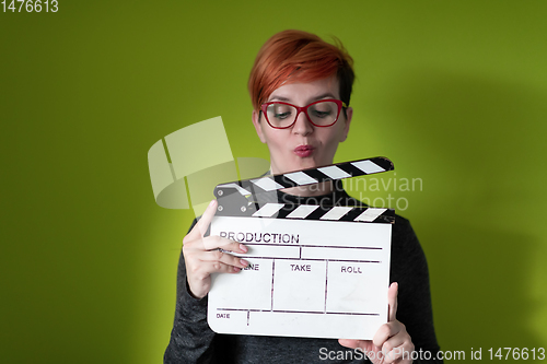 Image of redhead woman holding movie  clapper on green background