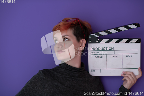 Image of redhead woman holding movie  clapper on purple background