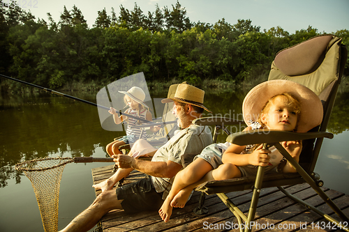 Image of Cute little girls and their granddad are on fishing at the lake or river