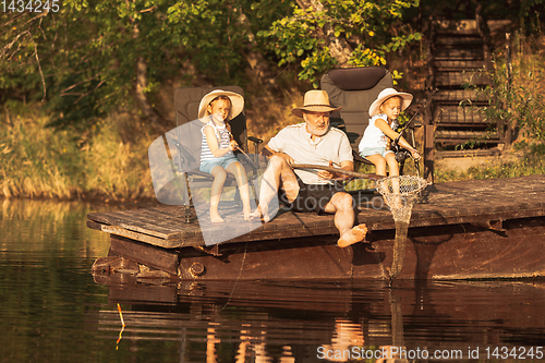 Image of Cute little girls and their granddad are on fishing at the lake or river