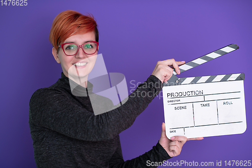 Image of redhead woman holding movie  clapper on purple background