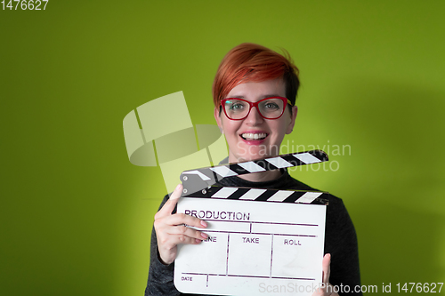 Image of redhead woman holding movie  clapper on green background